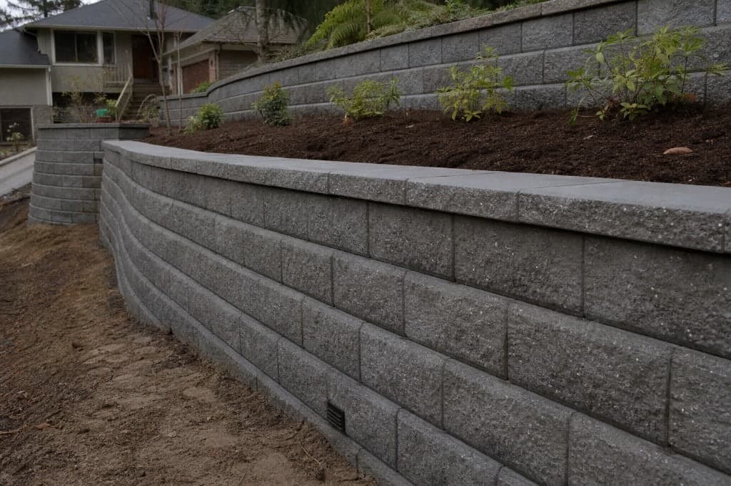 Curved segmental retaining walls and fresh planting on a residential slope.